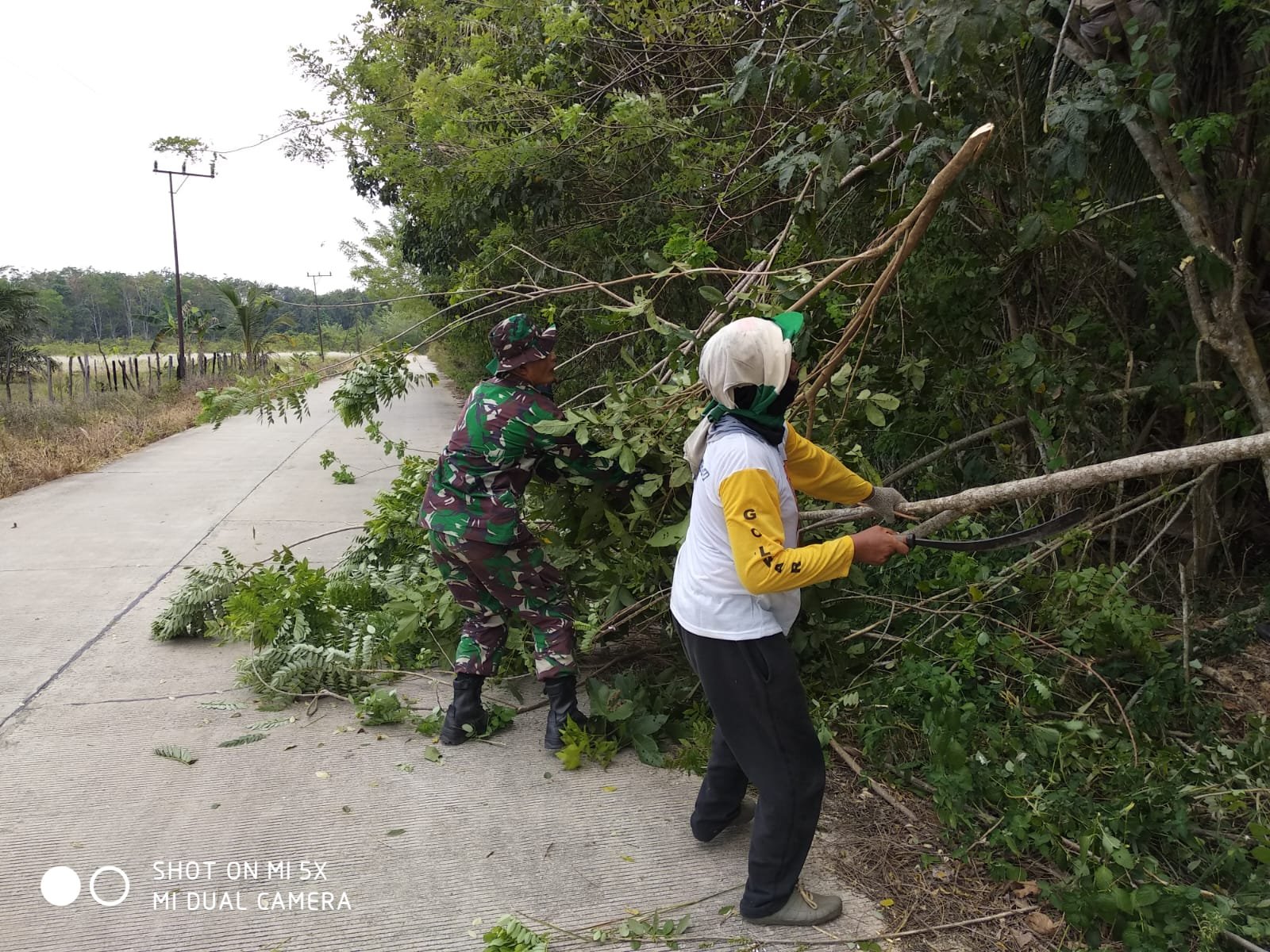 Babinsa Bersama Warga Lakukan Gotong Royong Bersihkan Dahan Pohon, Berikan Rasa Aman Pada Pengguna Jalan